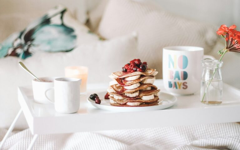 pancake with raspberries on plate beside mugs