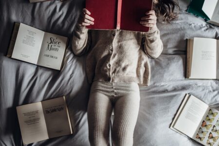 a little girl laying on a bed with lots of books