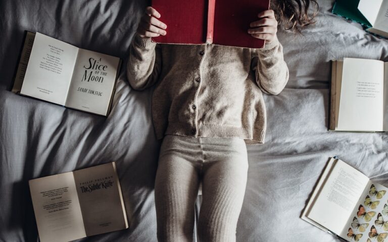 a little girl laying on a bed with lots of books