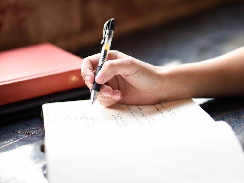 a person writing on a piece of paper with a pen