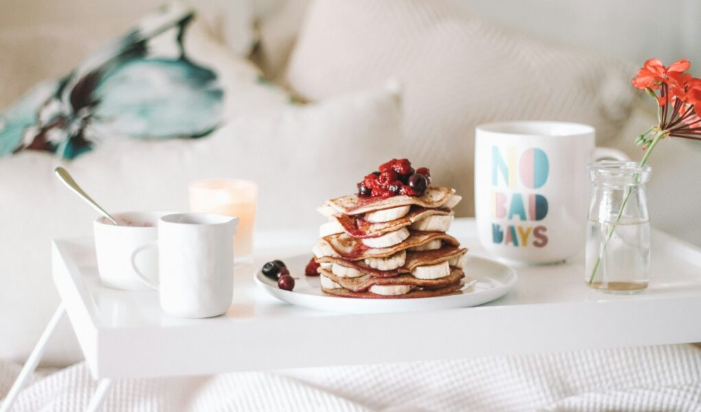 pancake with raspberries on plate beside mugs