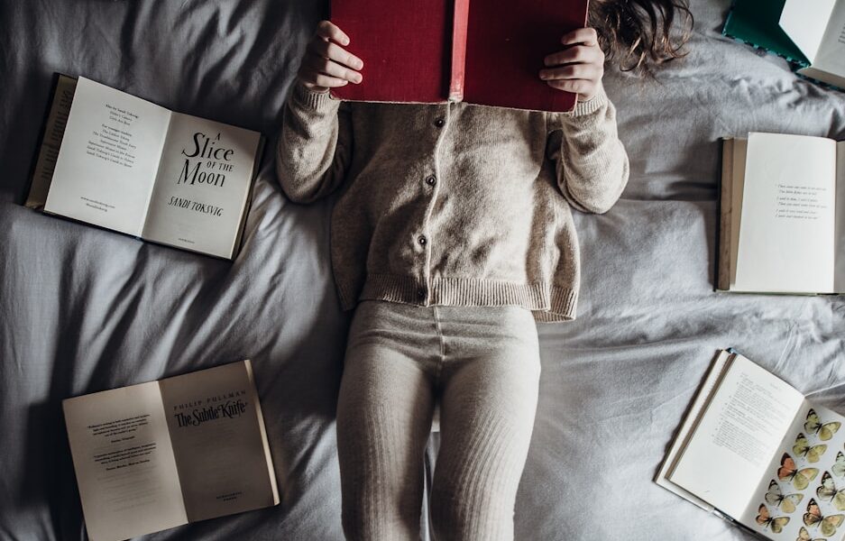 a little girl laying on a bed with lots of books